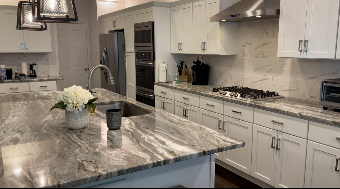 Spacious white kitchen with a large island and granite countertops. Stainless steel appliances and cabinets.