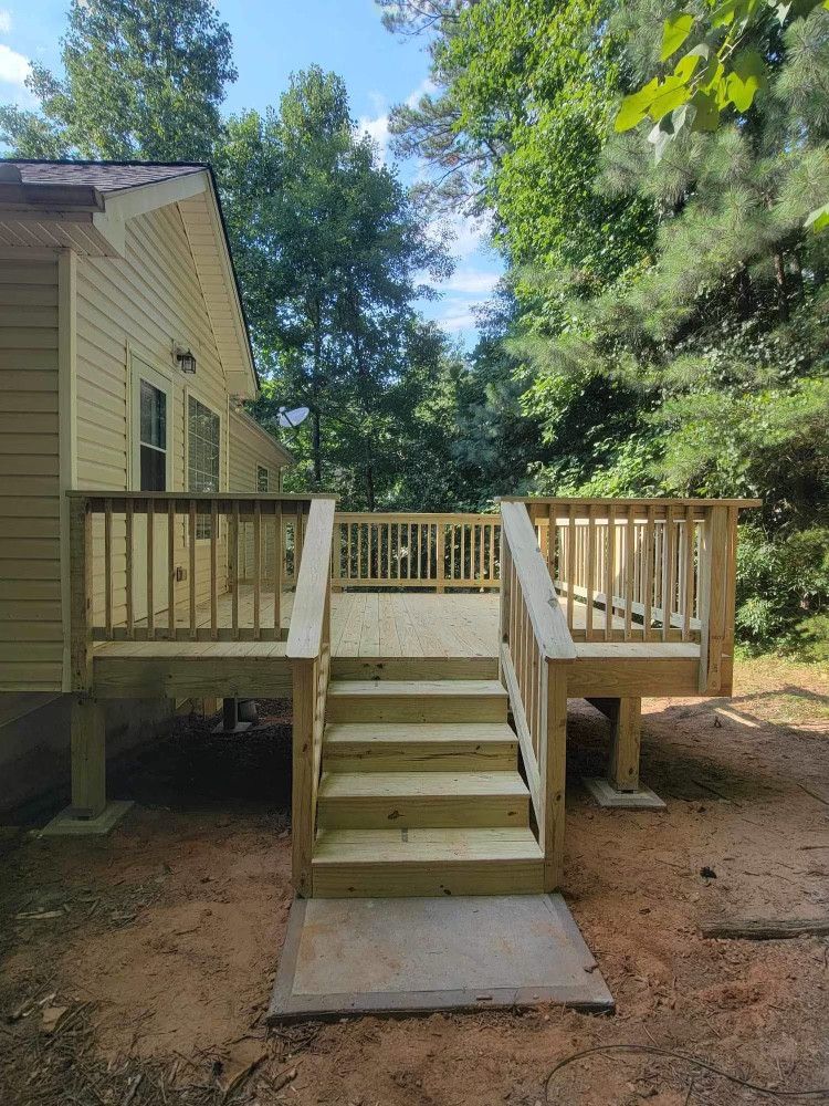 Wooden deck with stairs leading to a house, set in a natural outdoor environment. New construction with neutral colors.