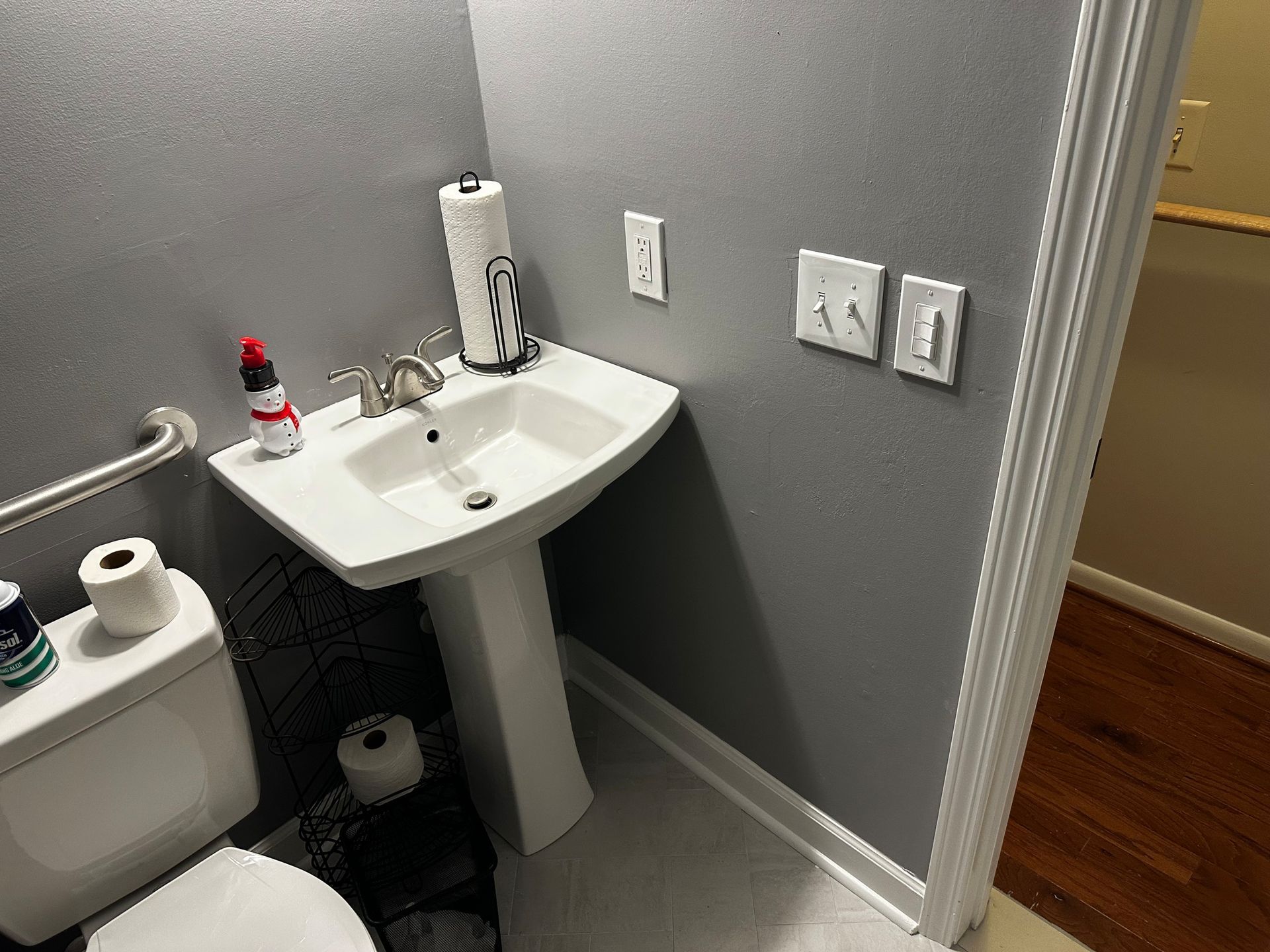 Small bathroom with a pedestal sink, toilet, and a doorway. The walls are gray.