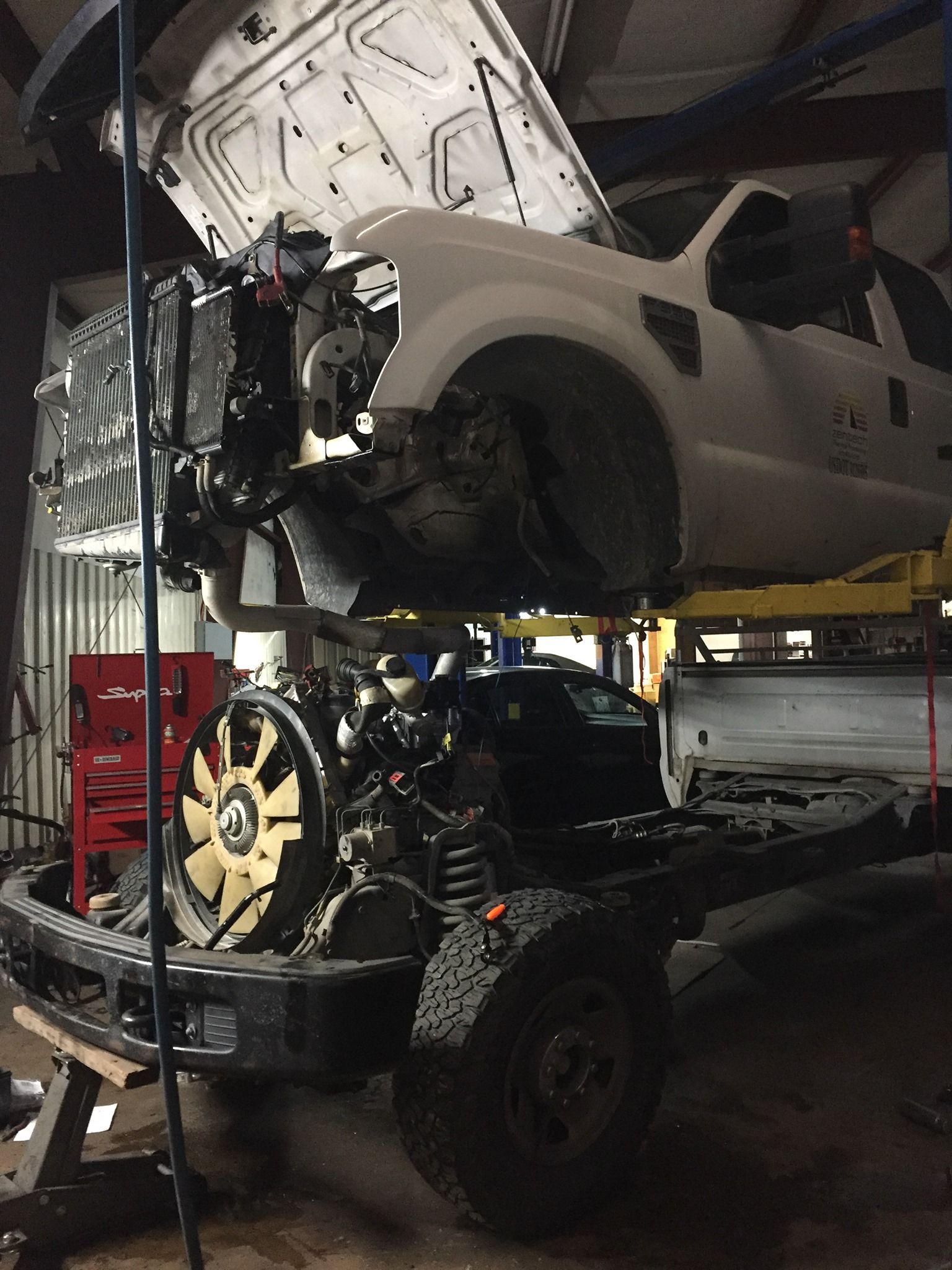 A truck with the hood up is being worked on in a garage.