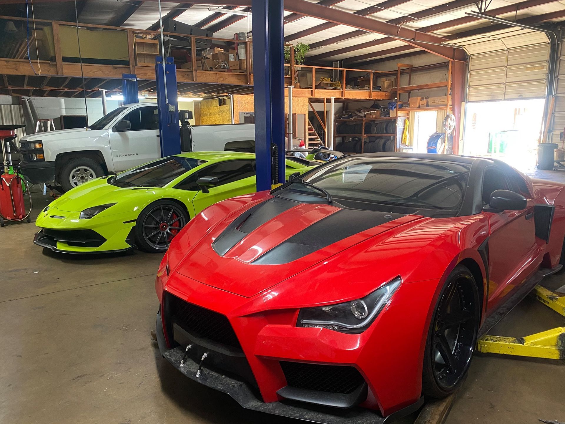 A red and a yellow sports car are parked in a garage.