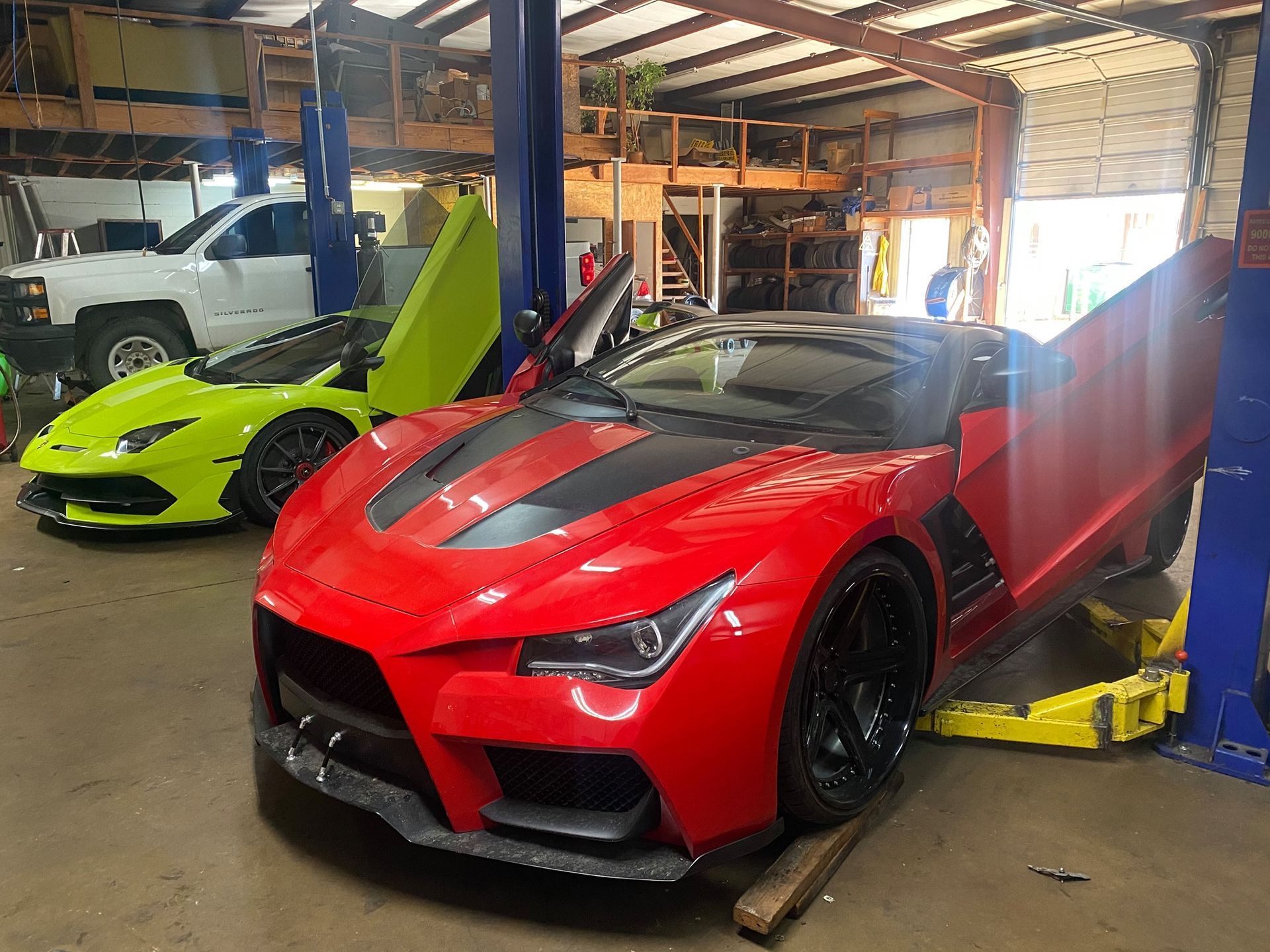 A red sports car is parked next to a yellow sports car in a garage.