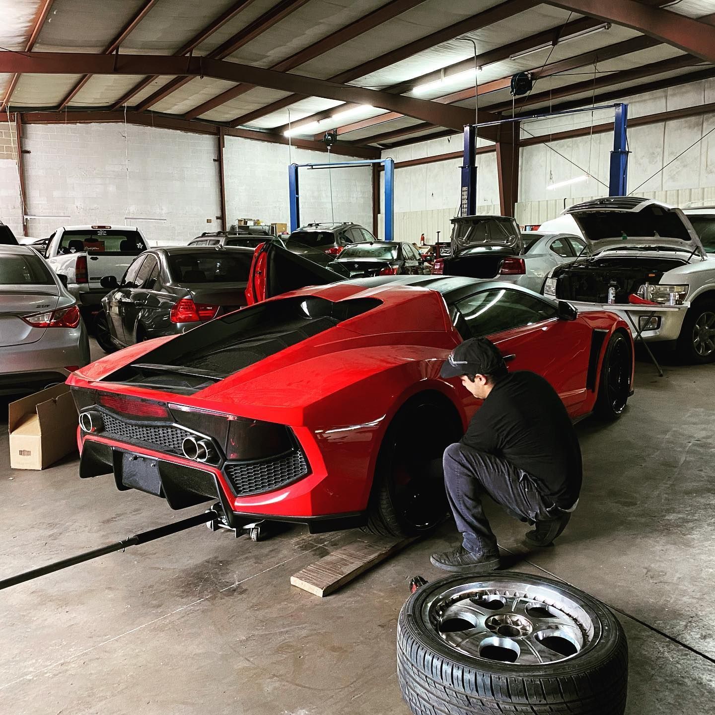 A man is working on a red sports car in a garage.