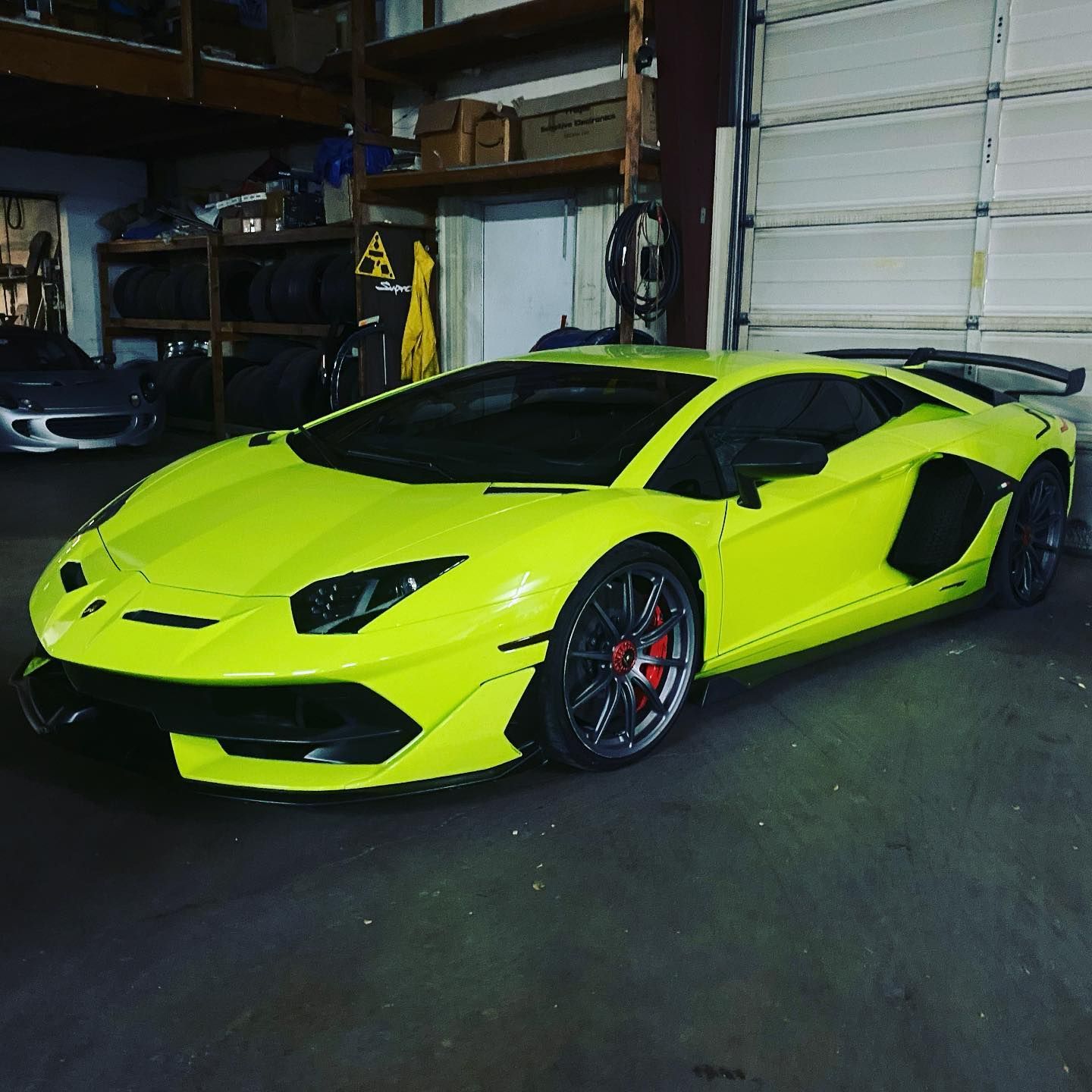 A bright yellow sports car is parked in a garage