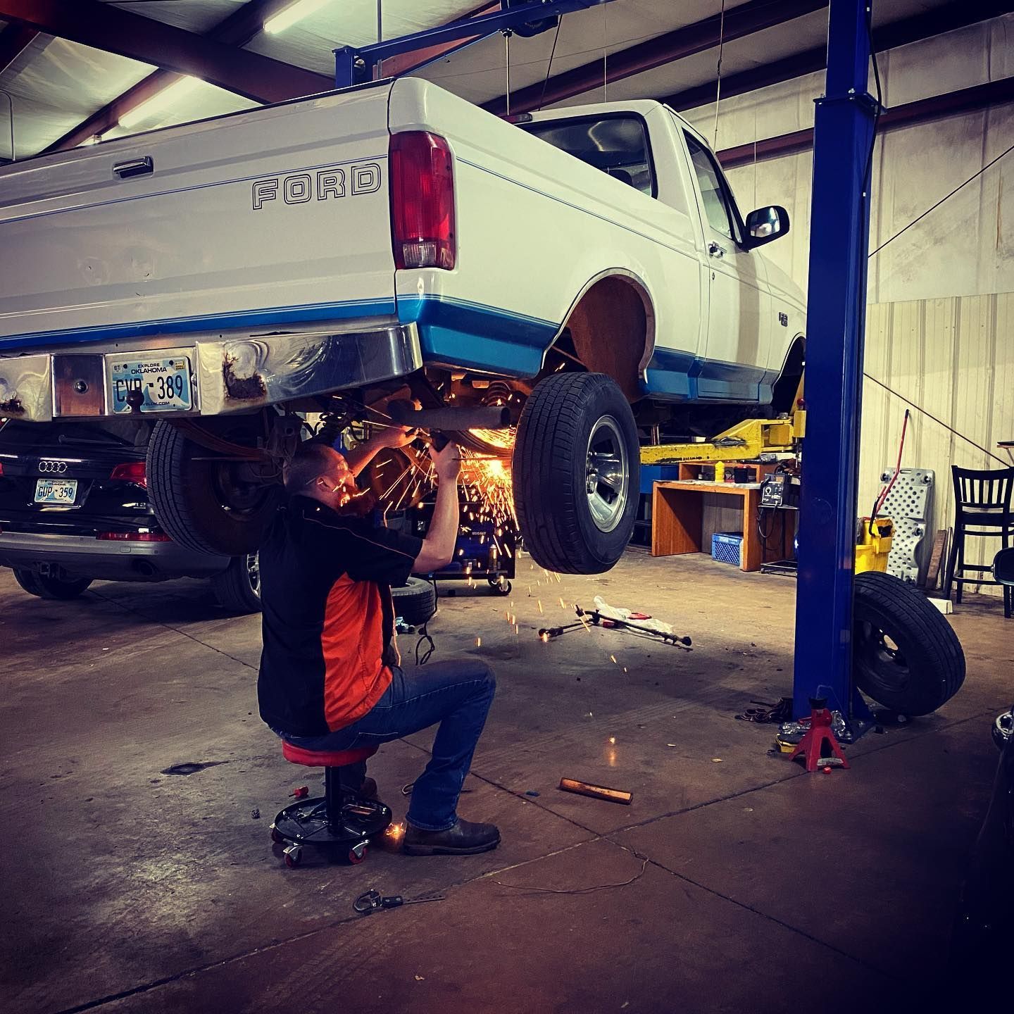 A man is working on a ford truck in a garage