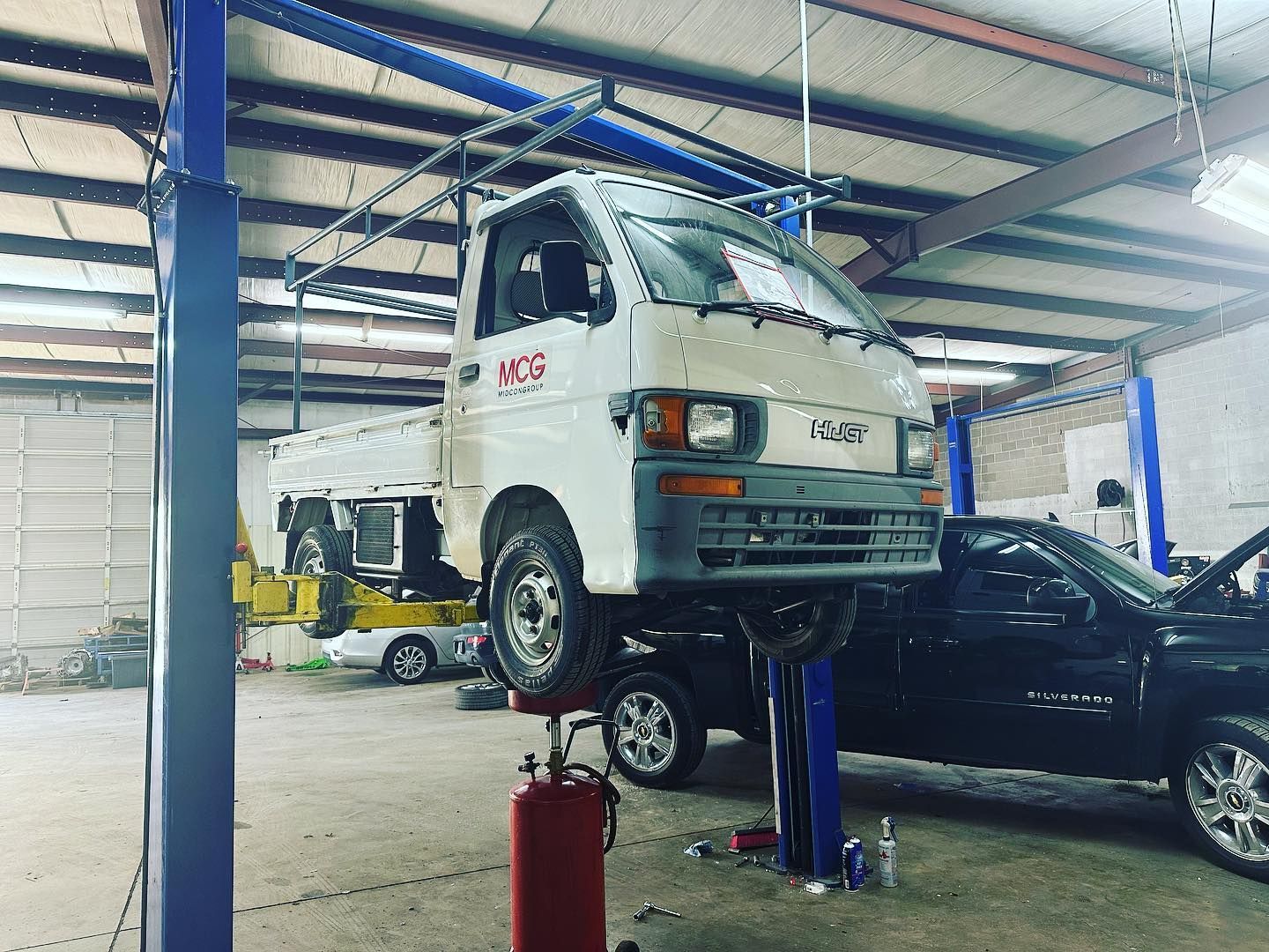 A white truck is sitting on a lift in a garage.