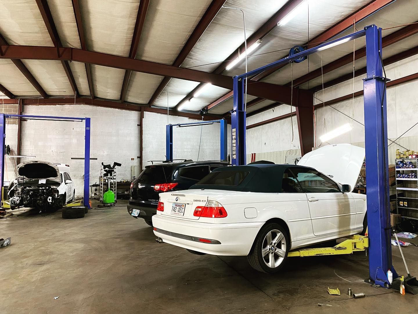 A white car is sitting on a lift in a garage.
