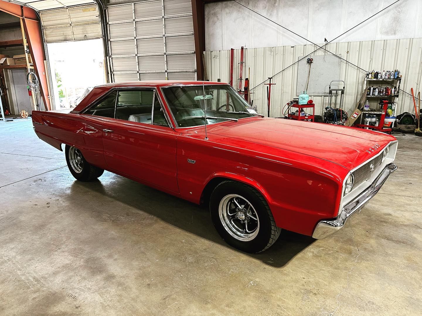 A red dodge charger is parked in a garage.