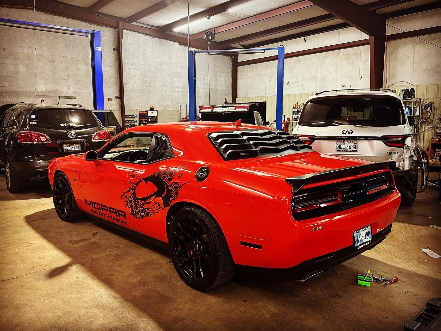 A red dodge challenger is parked in a garage.