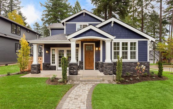 A blue and white house with a brick walkway leading to it.