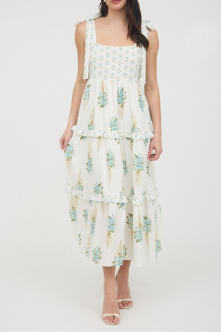 A woman is wearing a white dress with blue flowers on it.