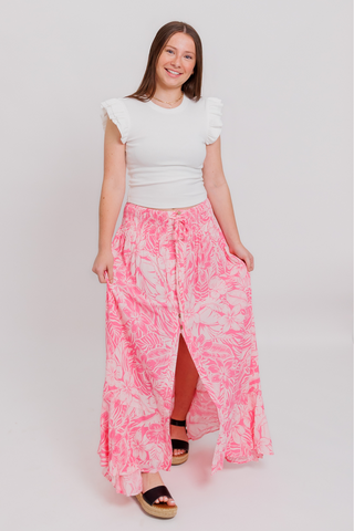 A woman is wearing a white t-shirt and a pink skirt.