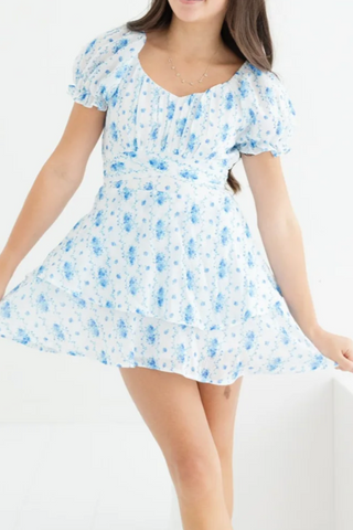 A woman is wearing a white dress with blue flowers on it.