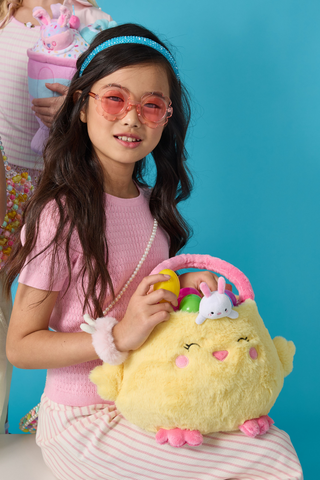 Child holding a plush yellow bunny basket with colorful eggs, wearing a pink outfit.
