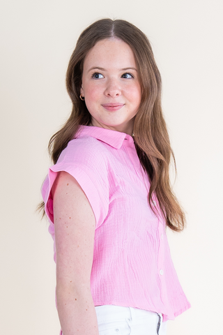 A young girl is wearing a pink shirt and white jeans.