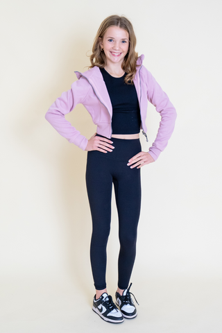 The girl is wearing a pink jacket and black leggings.