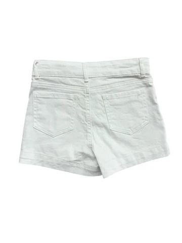 A young girl wearing a black crop top and white shorts is smiling.