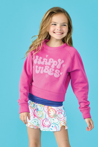 A little girl is wearing a pink sweatshirt and a white skirt.