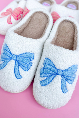 A pair of white slippers with blue bows on them