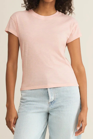 A woman is wearing a pink t-shirt and blue jeans