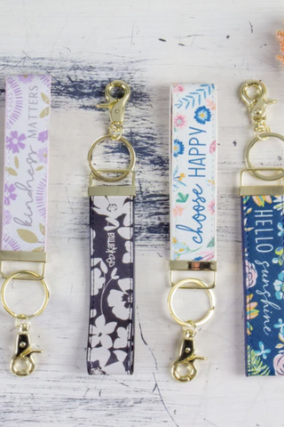 Three keychains are sitting on a wooden table.