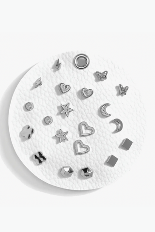 A white plate topped with a variety of silver stud earrings.