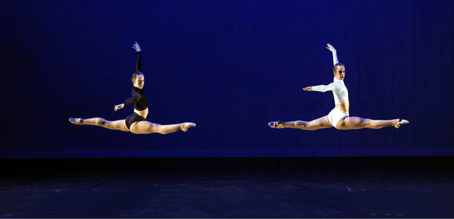 Two dancers are doing splits in the air on a stage.