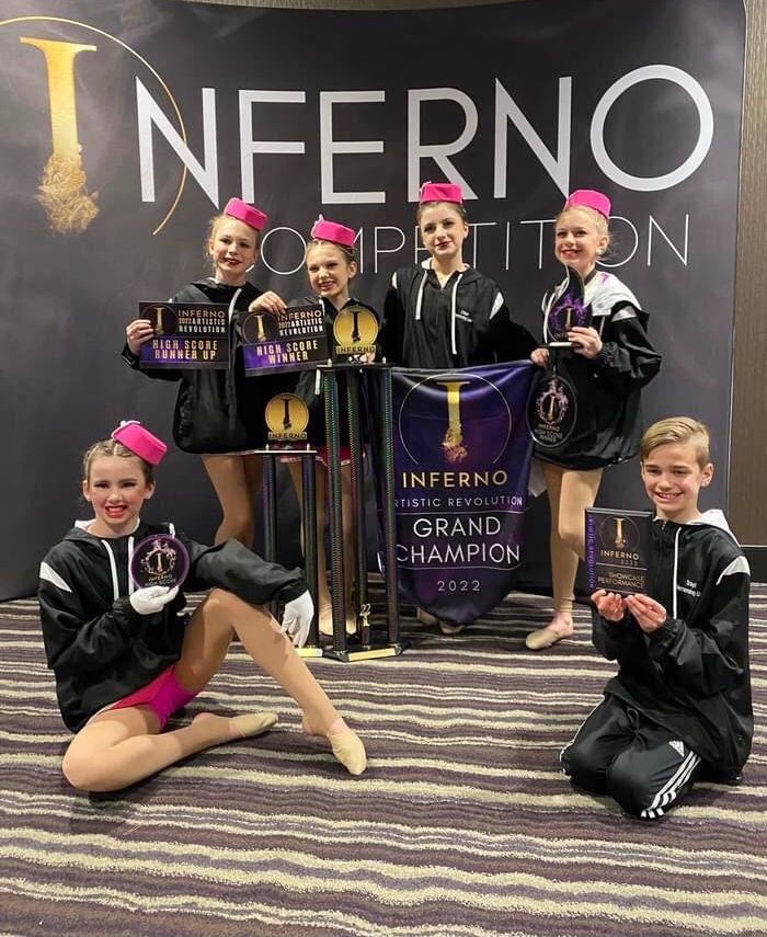 A group of young dancers are posing for a picture in front of a sign that says Inferno Competition