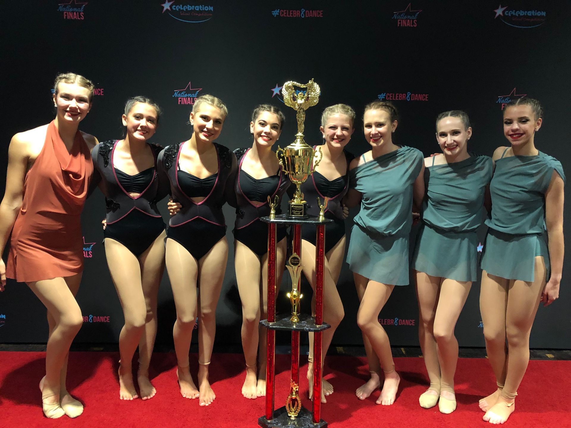 A group of young women standing next to a trophy