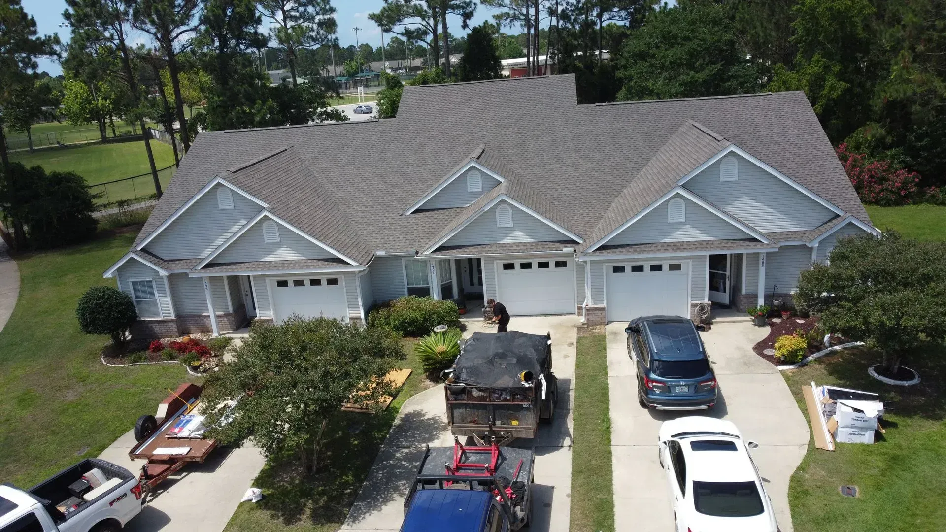 Blue duplex with three garage doors. Trucks and equipment parked in front during renovation.
