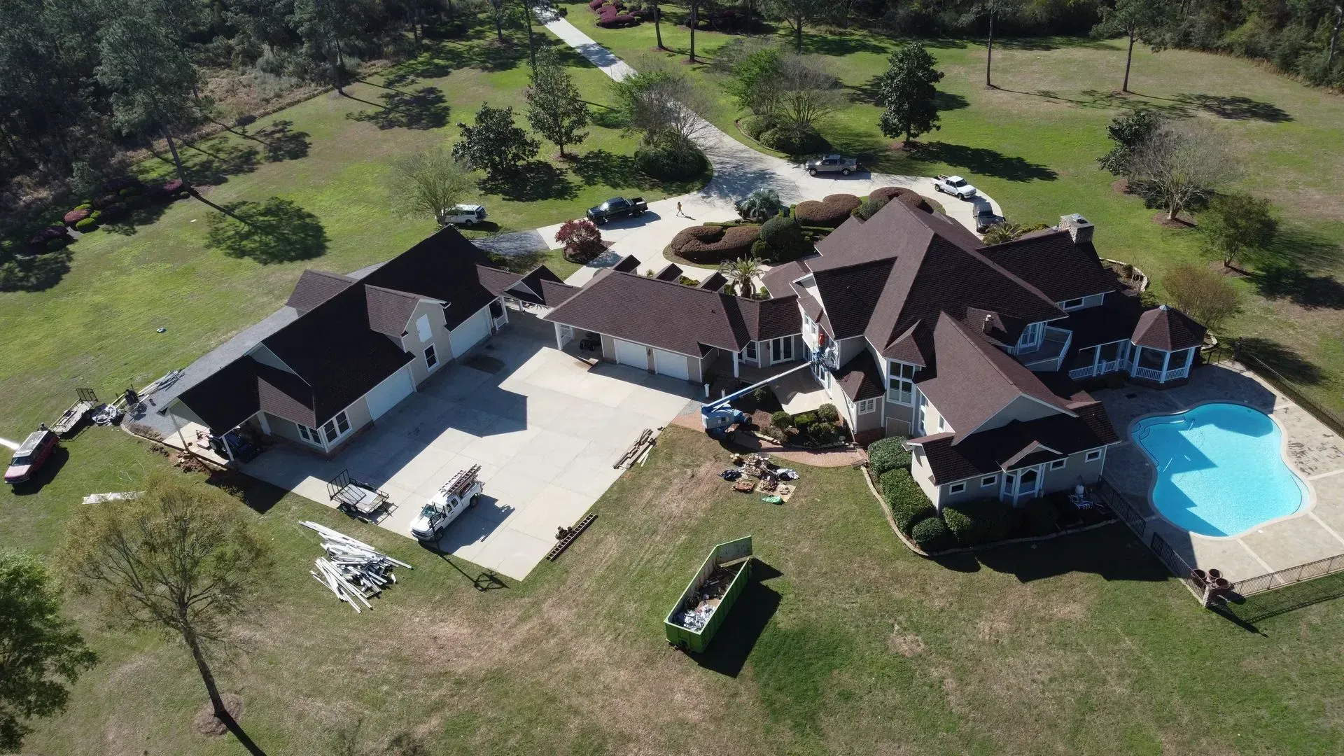 Aerial view of a large house with a pool and detached garage on a grassy lot.