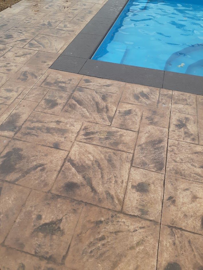 Stamped concrete pool deck with water and dark border.