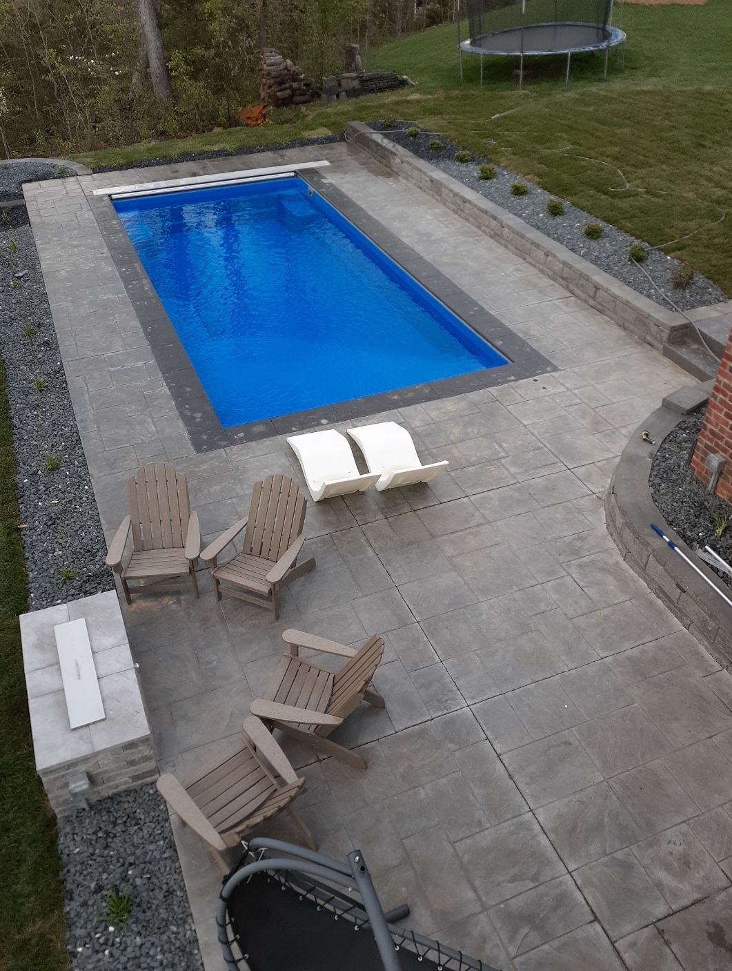 An aerial view of a swimming pool with chairs and a fire pit.