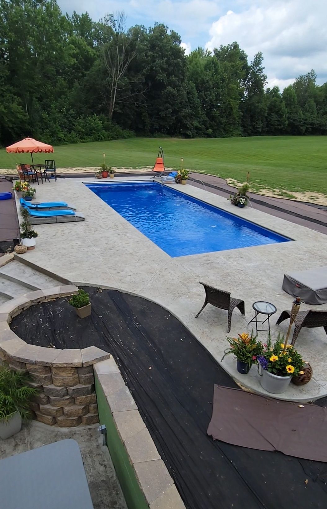 There is a large swimming pool in the middle of a lush green field.