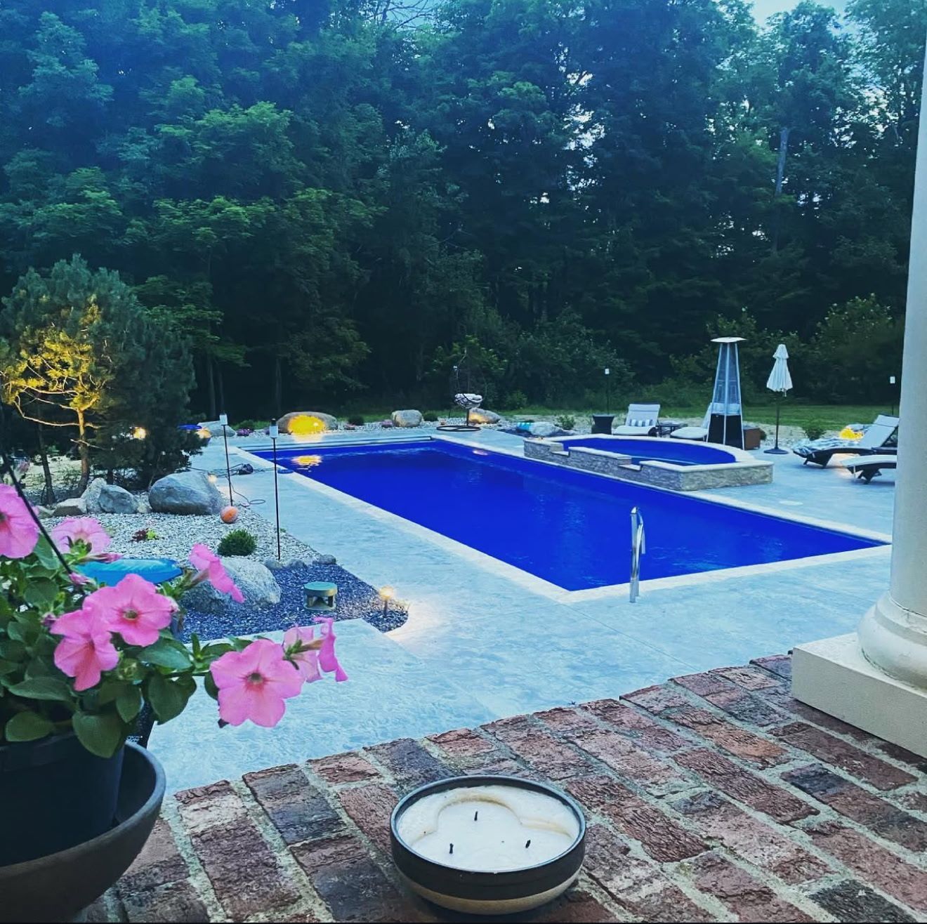 A candle sits in front of a large swimming pool.