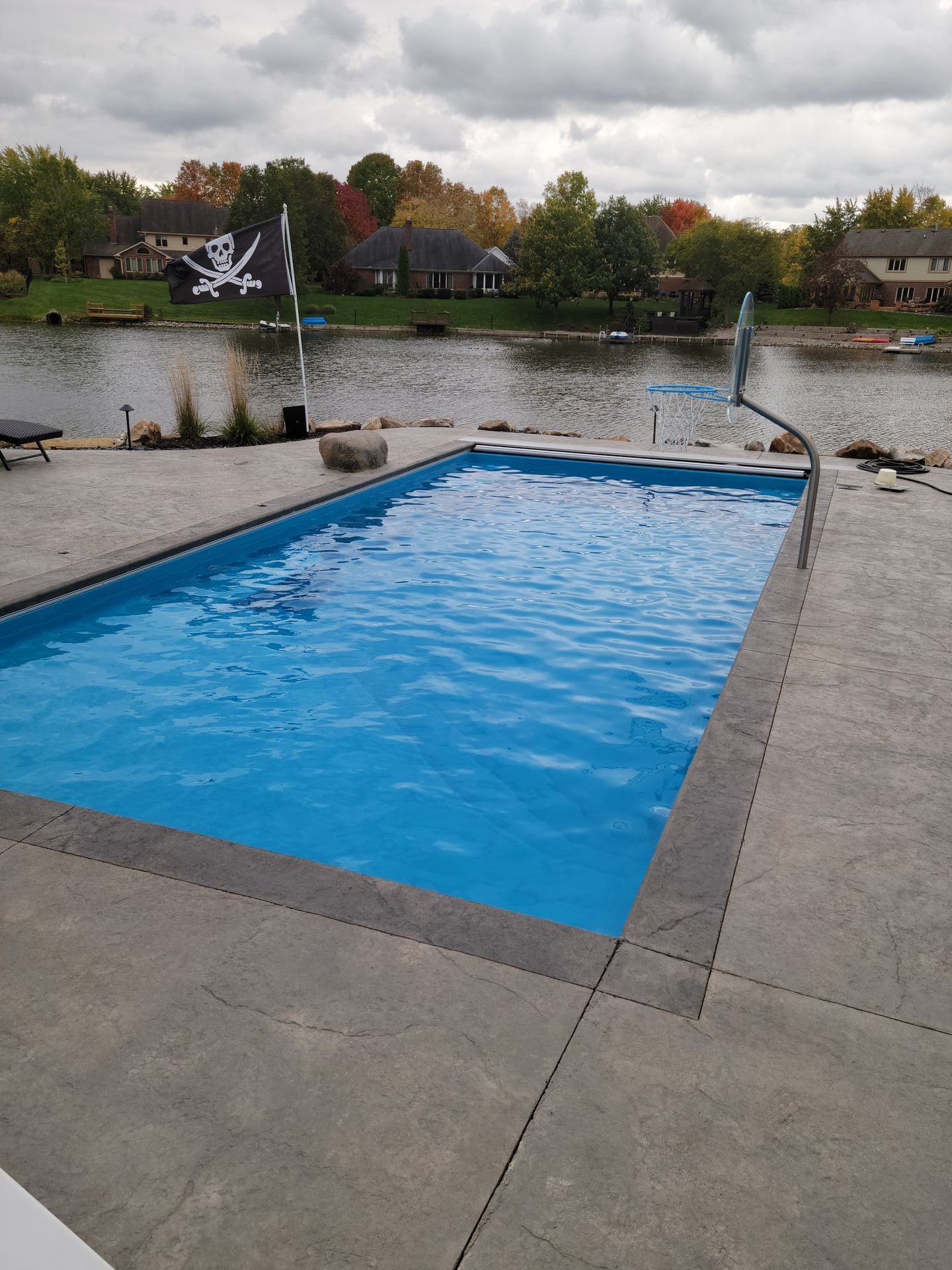 A large swimming pool is sitting next to a lake.