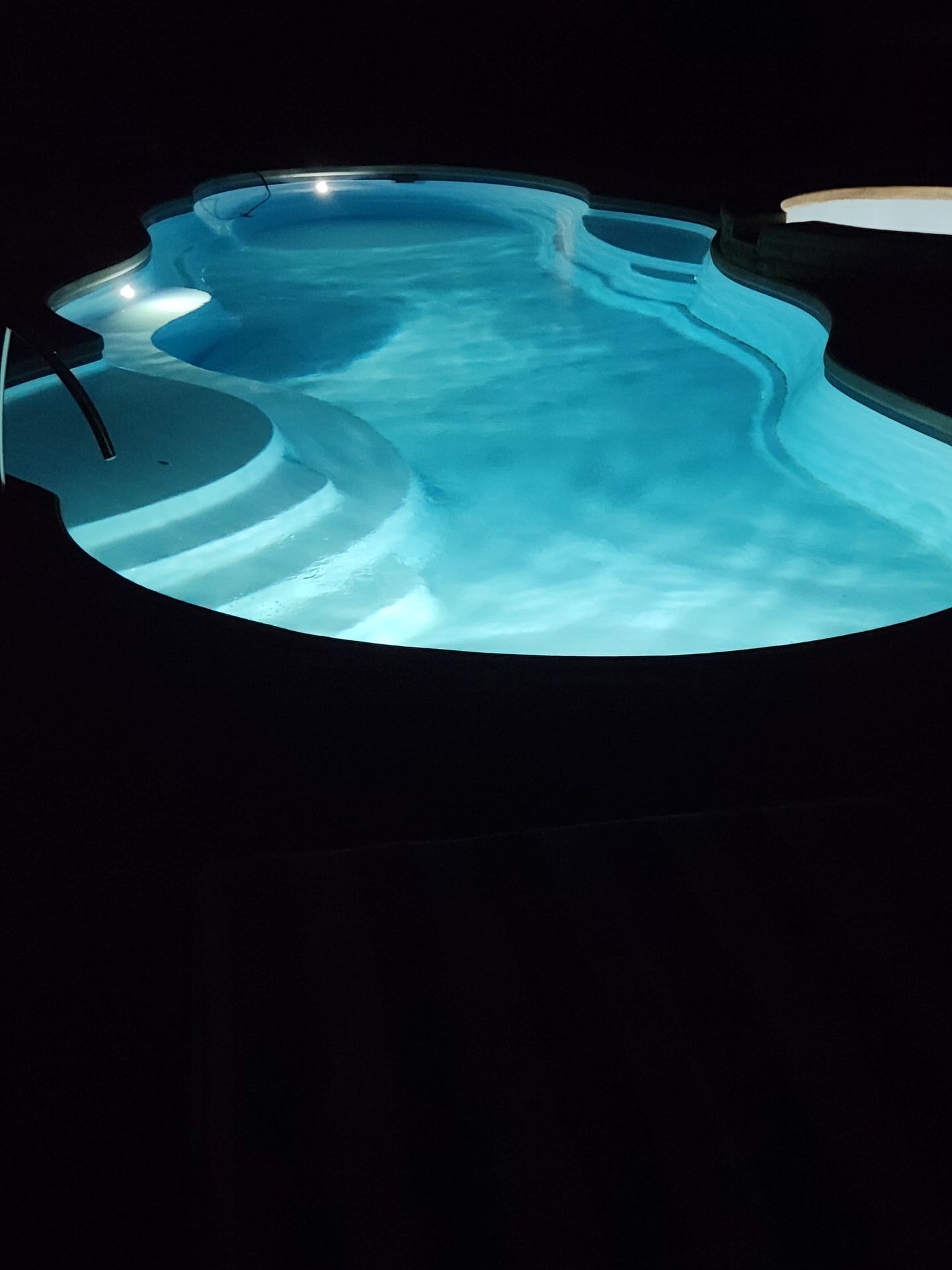 A large swimming pool is lit up at night.