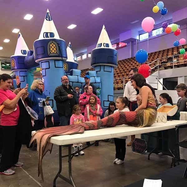 A group of people standing around a table with a mermaid on it