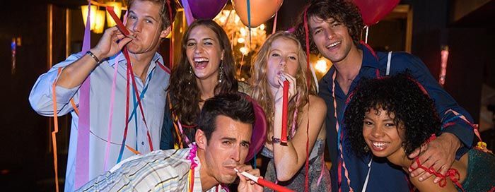 A group of people are blowing party horns at a party.