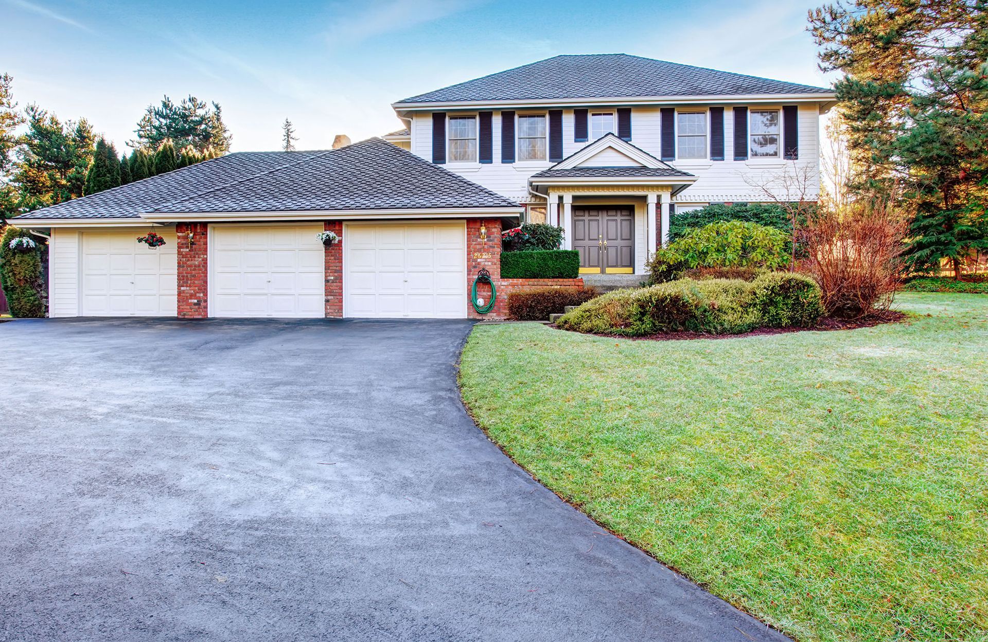 A large house with two garage doors and a driveway leading to it.