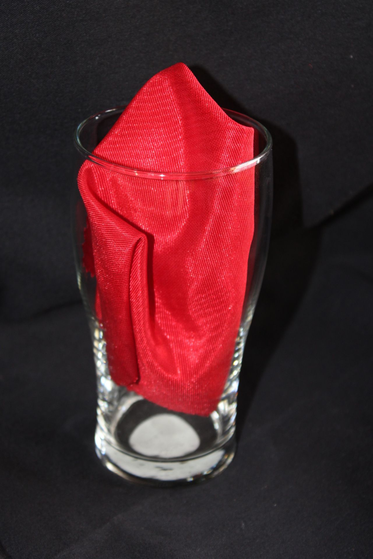 A tall glass with a red napkin in it