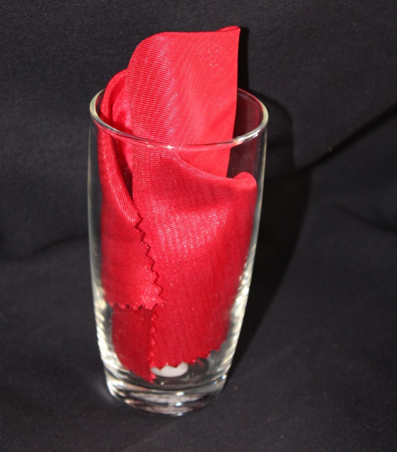 A tall glass with a red napkin in it