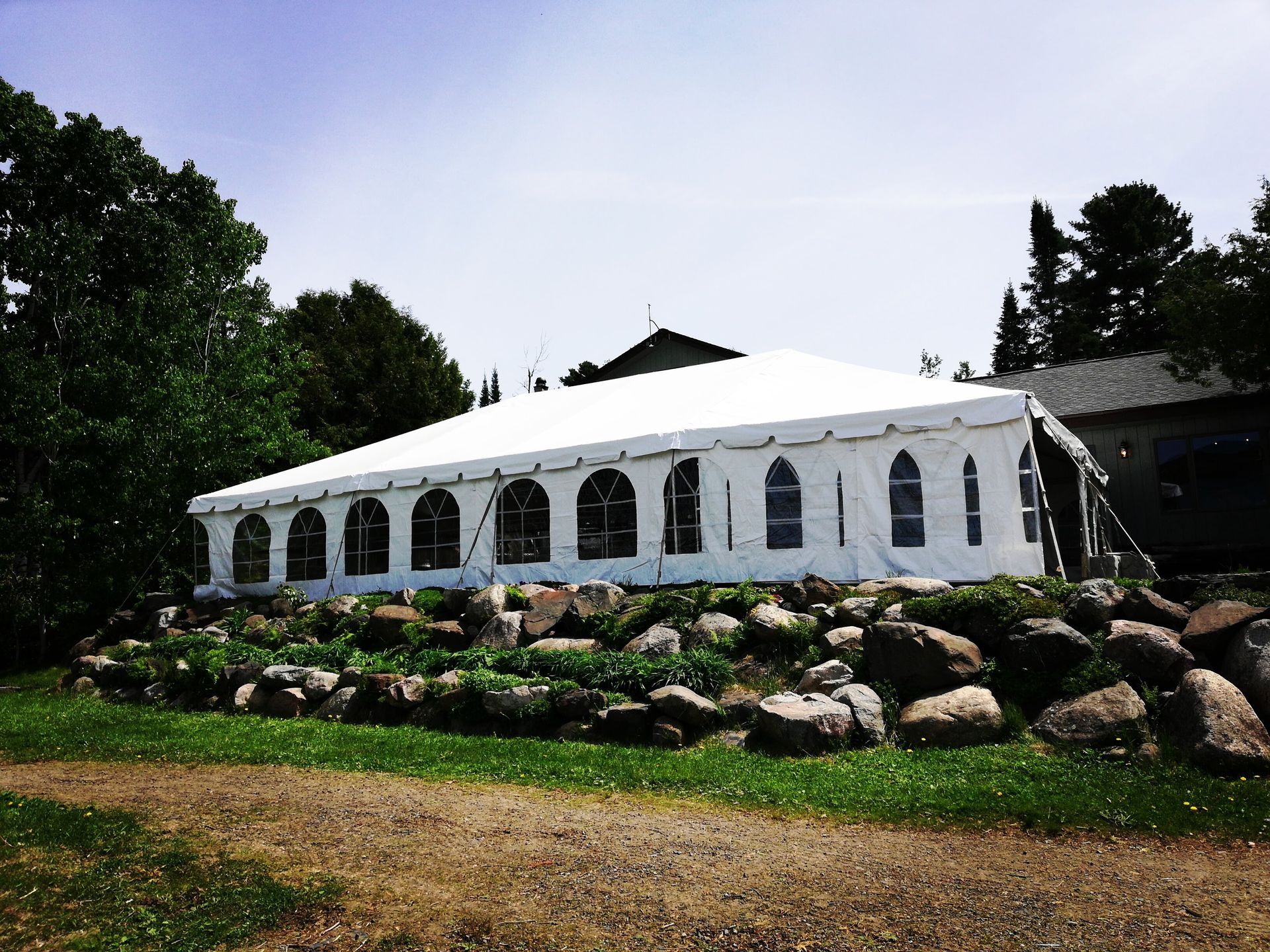 A large white tent is sitting on top of a rocky hill.