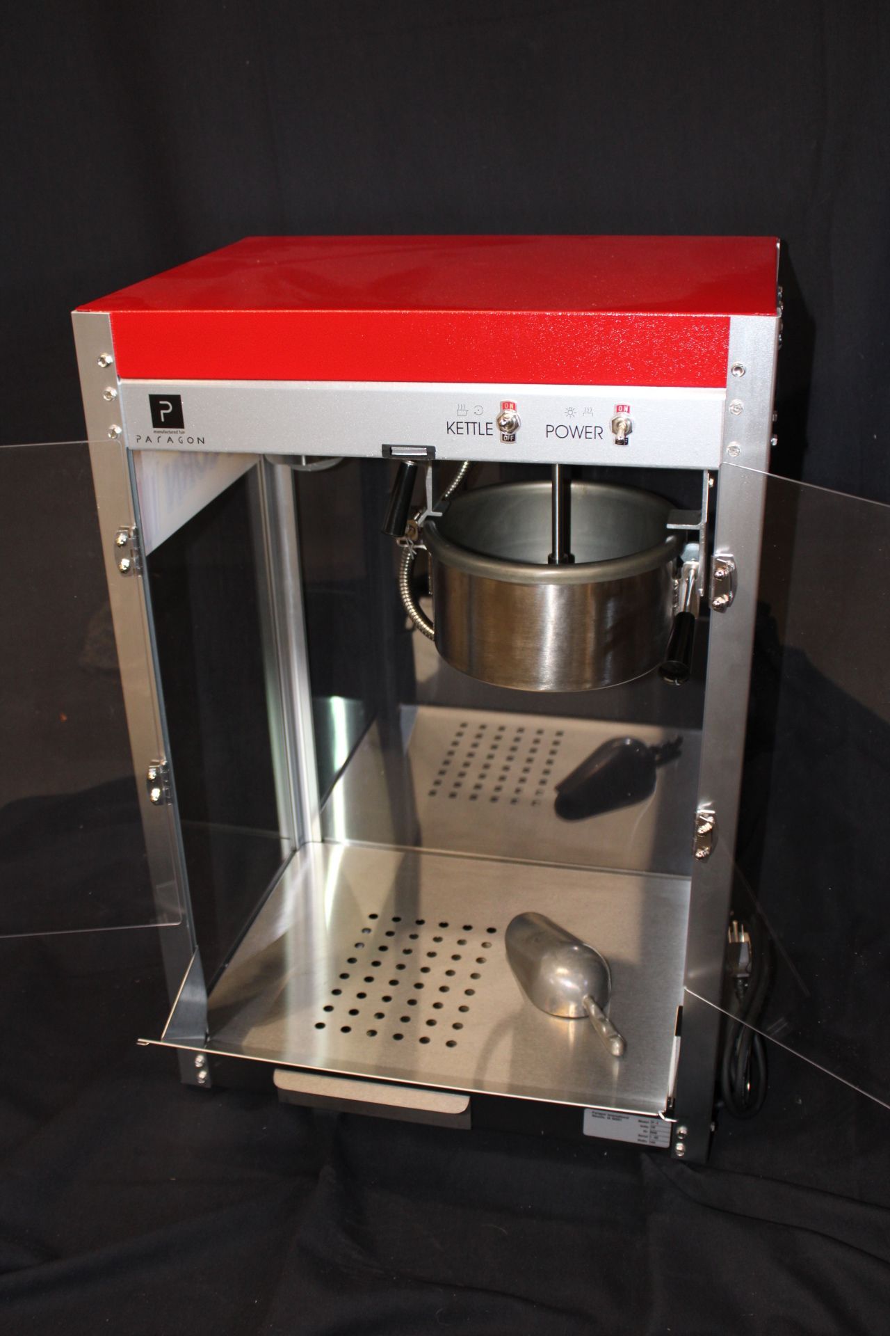 A popcorn machine with a red top is sitting on a black table.