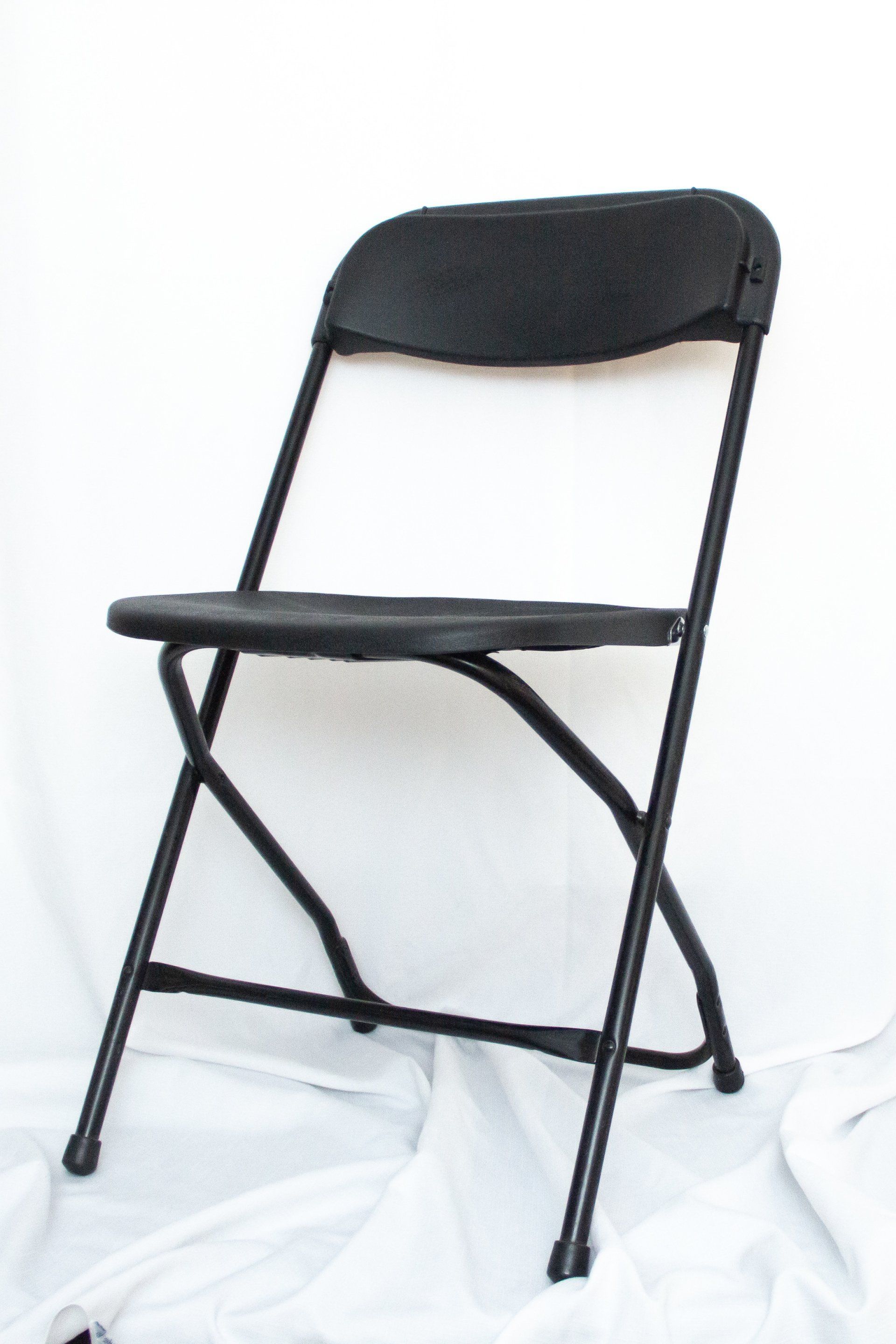A black folding chair is sitting on a white cloth