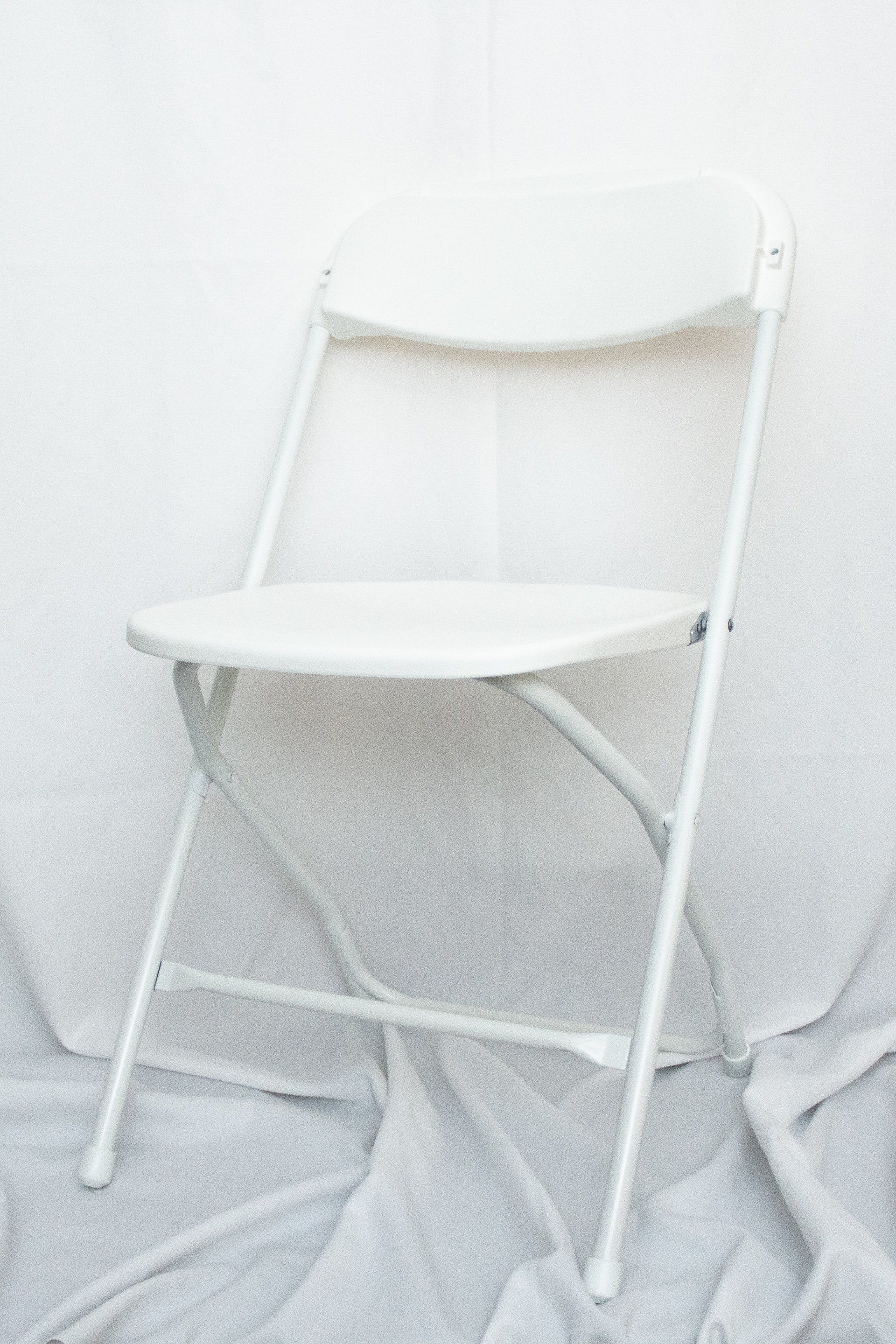 A white folding chair is sitting on a white cloth.