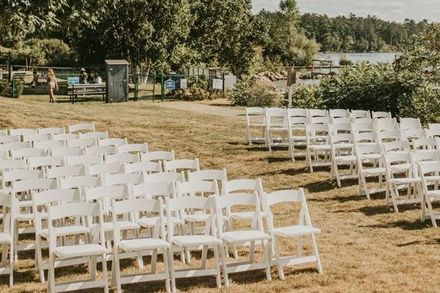 a row of white folding chairs are lined up in a field .