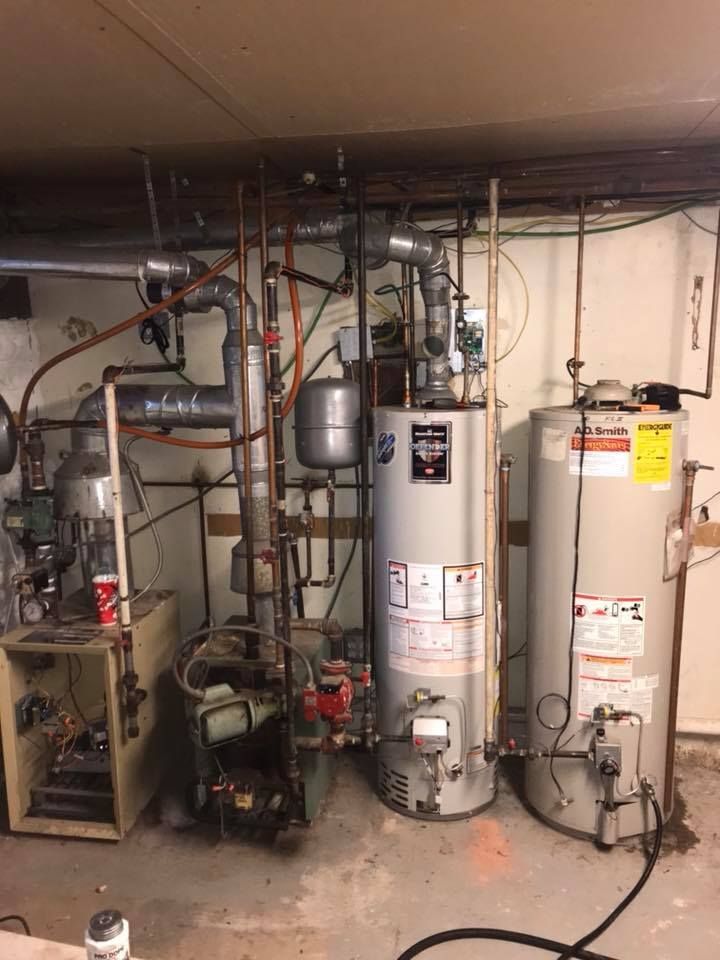 Two water heaters are sitting next to each other in a basement.