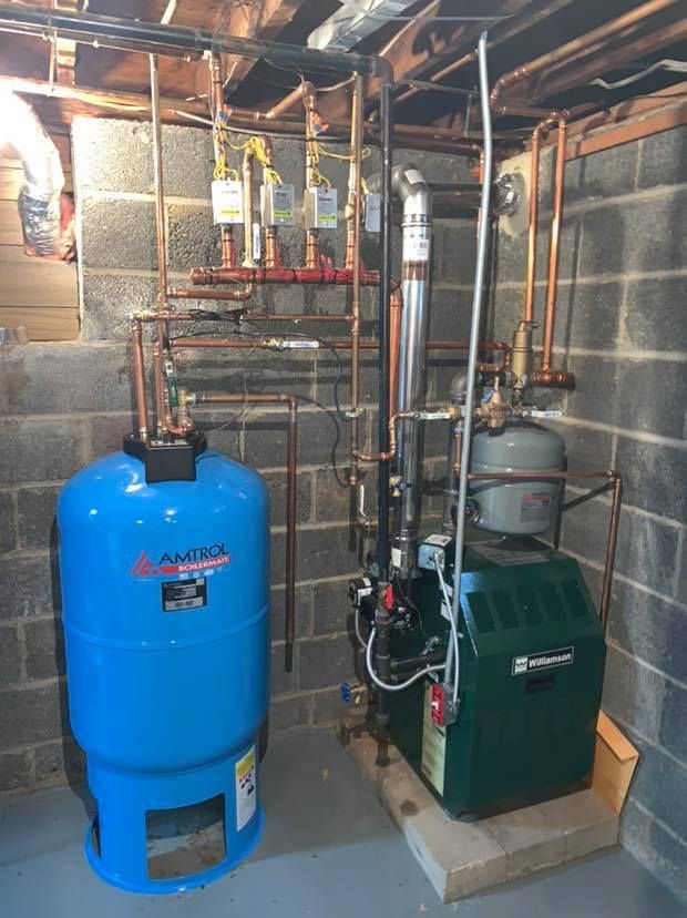 A blue water tank is next to a green boiler in a basement.