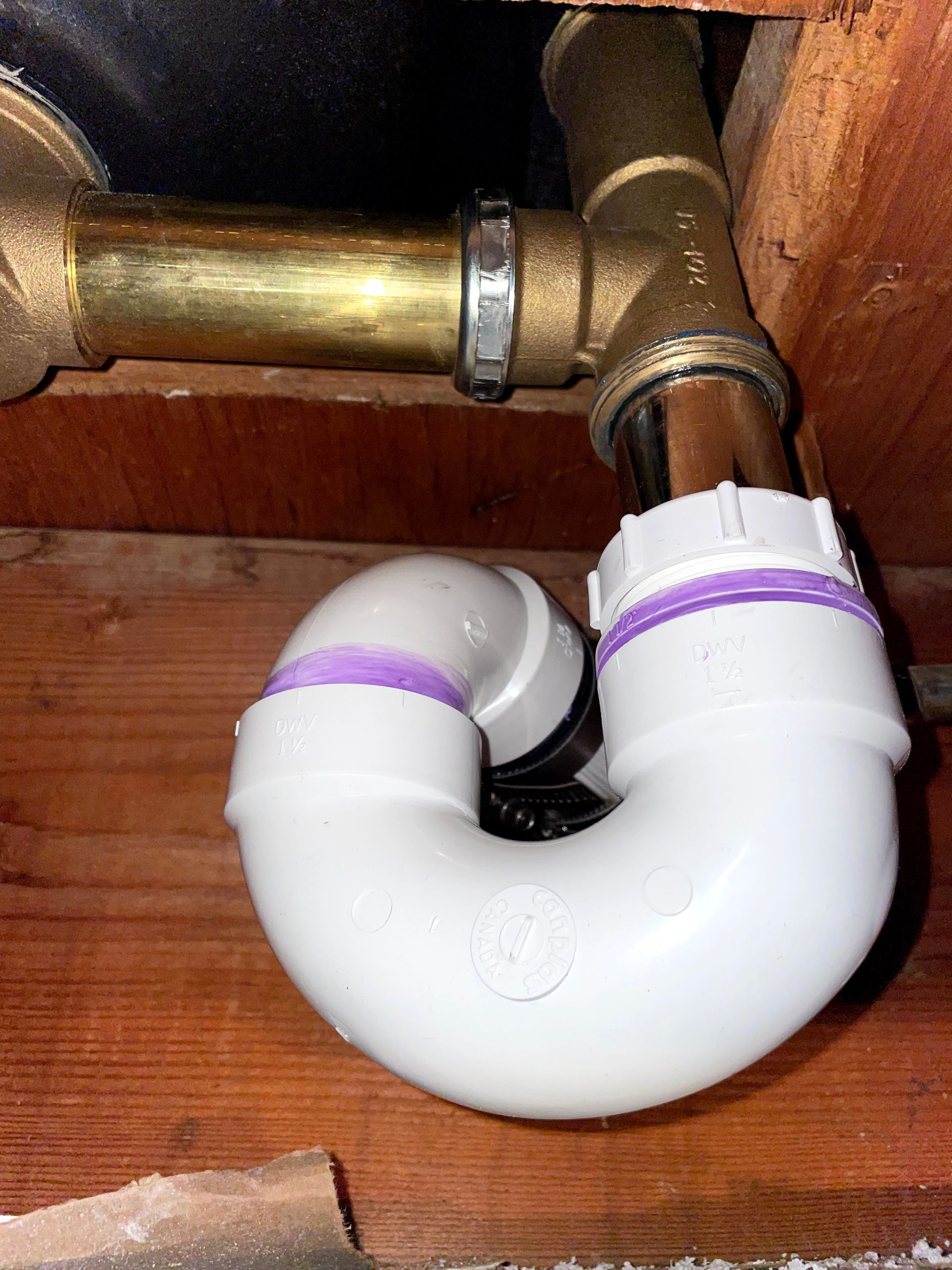 A white pipe is connected to a brass pipe.